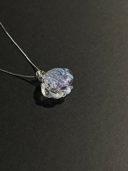 Shell-shaped glass necklace pendant with a birthstone-colored center against a dark background.