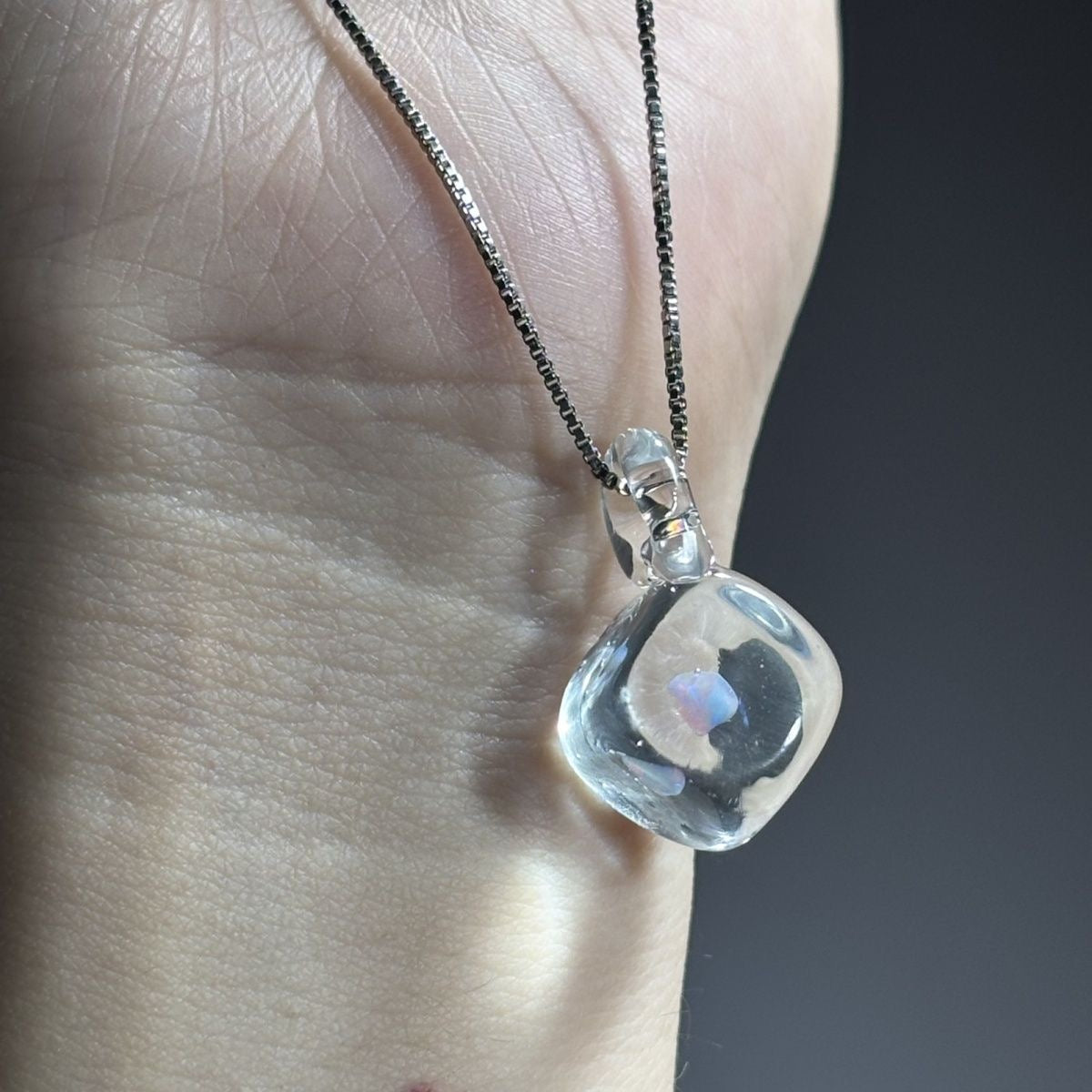 Clear opal glass pendant held in front of a hand to show its size.