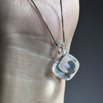 Clear opal glass pendant held in front of a hand to show its size.